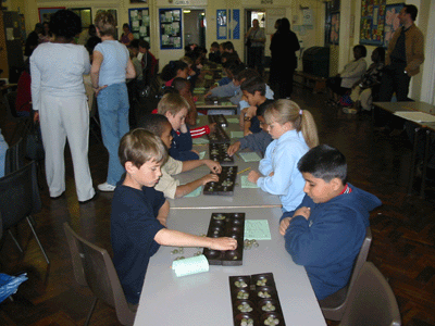 Junior players engaged in a game with parents & teachers in the background